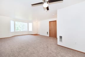 an empty living room with a ceiling fan and a window