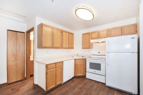 an empty kitchen with white appliances and wooden cabinets