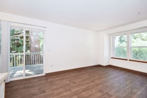 an empty living room with wood floors and a door to a balcony
