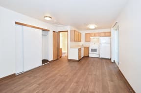 an empty kitchen with white appliances and wood floors