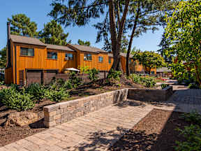 a brick walkway leading up to a house with trees and a courtyard