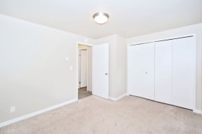 a bedroom with white walls and white closets and carpet