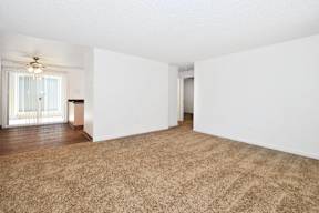 an empty living room with white walls and a ceiling fan