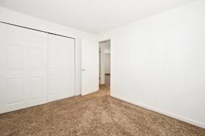 an empty bedroom with a closet and a door to a hallway