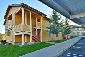 a yellow building with a porch and stairs on the side of it