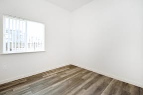 a room with white walls and wood floors and a window