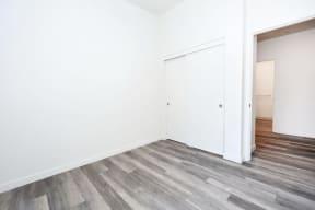 a bedroom with white walls and wood flooring and a closet