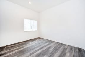 a room with white walls and wood flooring and a window