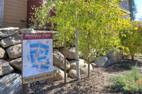 a sign in front of a building with trees and rocks in the background