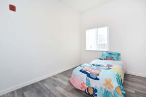 a bedroom with white walls and a bed with a colorful bedspread and a window