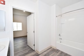 a renovated bathroom with a shower and a sink and a door to a bedroom