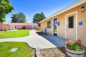 A building with a pink and beige exterior has a walkway leading to the front door.