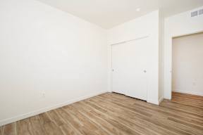A room with a white door and wooden flooring.