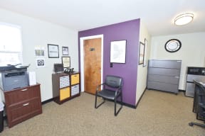 an office with a purple wall and a desk with a chair