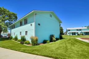 a blue house with a lawn in front of a building