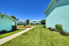 a walkway between two buildings with grass and a sidewalk