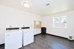 an empty laundry room with two washers and dryers and a window