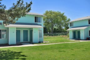 the homes are painted in blue and turquoise with a lawn and trees