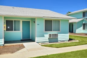 the front of a blue house with a sidewalk and grass