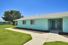 the front of a blue house with a sidewalk and grass