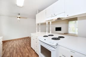 an empty kitchen with white cabinets and a white stove