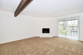 an empty living room with a fireplace and a patio door