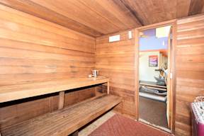 A wooden room with a bench and a doorway leading to another room.