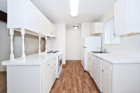 a white kitchen with wood floors and white cabinets