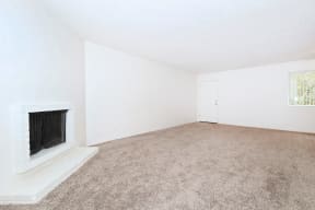 an empty room with a fireplace and a carpeted floor