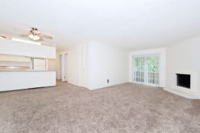 an empty living room with a kitchen and a ceiling fan