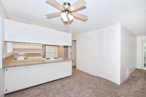 an empty kitchen with white cabinets and a ceiling fan