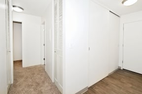 a bedroom with white walls and wood flooring and a closet