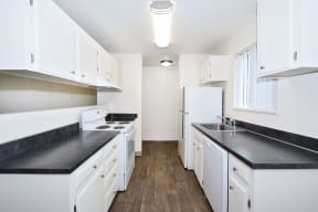 a white kitchen with black counter tops and white appliances