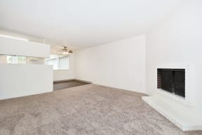 an empty living room with a fireplace and a carpeted floor