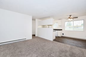 an empty living room and kitchen with a ceiling fan