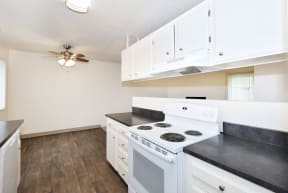 an empty kitchen with white appliances and a ceiling fan