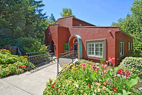 A red house with a garden in front.