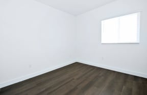an empty room with white walls and wood floors and a window