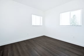 an empty room with white walls and wood floors and a window