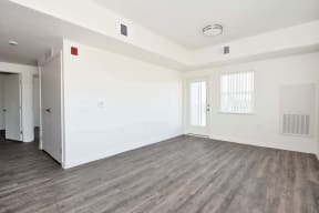 the living room of an apartment with white walls and hardwood floors