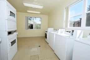 a laundry room with washers and dryers and windows