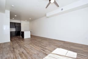 an empty living room and kitchen with a ceiling fan
