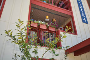 a balcony with a red railing and a window box filled with flowers