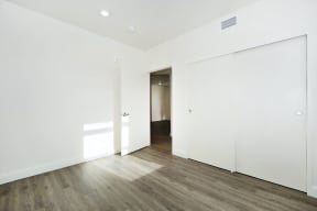 a bedroom with white walls and wood floors