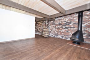 a room with a wood floor and a brick wall with a spiral staircase in front of it