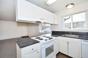Menlo Manor: kitchen with white cabinets and a white stove top oven