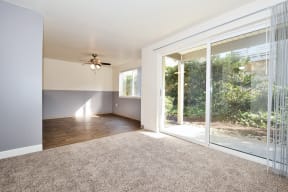 an empty living room with a sliding glass door and a ceiling fan