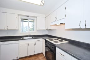 The Firs:  a kitchen with white cabinets and black countertops