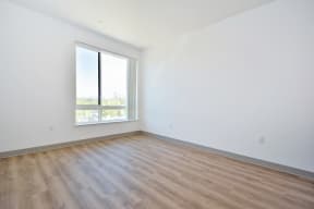 a bedroom with hardwood floors and a large window
