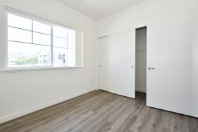 a bedroom with white walls and hardwood floors